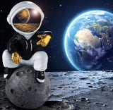 BRUBAKER Figurine Astronaut Sits on The Moon in a Cool Pose - 9.5 Inch Spaceman Space Decor Figure with Chromed Helmet and Black Hoodie - Hand Painted - Gold, Black and White