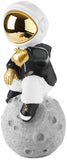 BRUBAKER Figurine Astronaut Sits on The Moon in a Cool Pose - 9.5 Inch Spaceman Space Decor Figure with Chromed Helmet and Black Hoodie - Hand Painted - Gold, Black and White